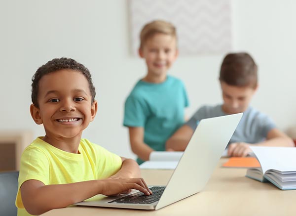 schoolboy e-learning on laptop during computer class in classroom